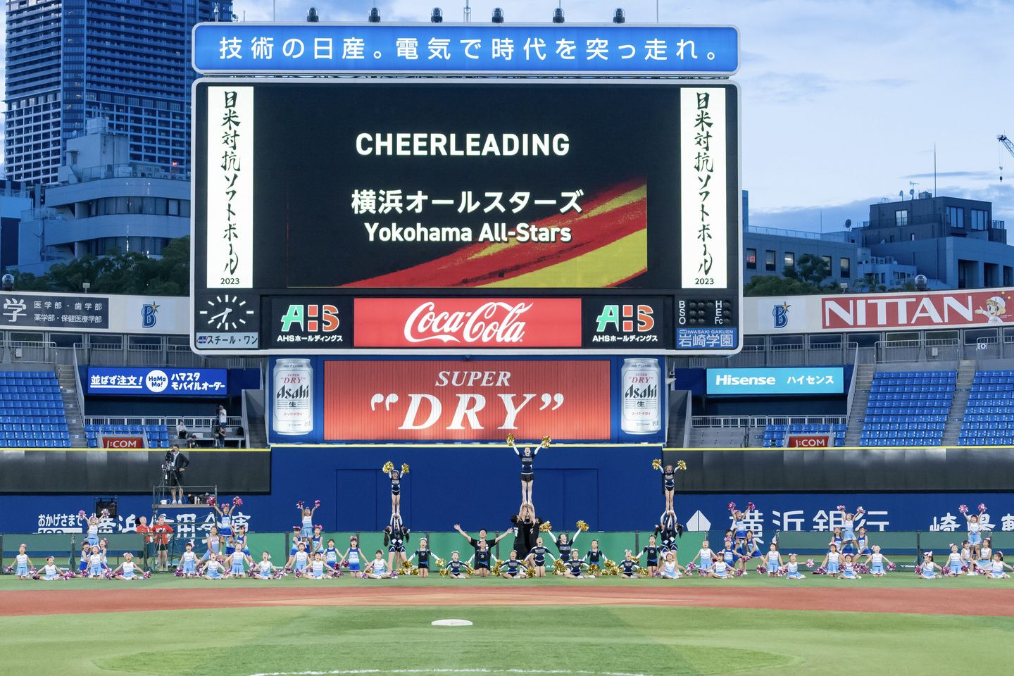 球場の大きな画面に「横浜オールスターズ Yokohama All-Stars」の文字。グラウンドで演技するチアリーダーたち